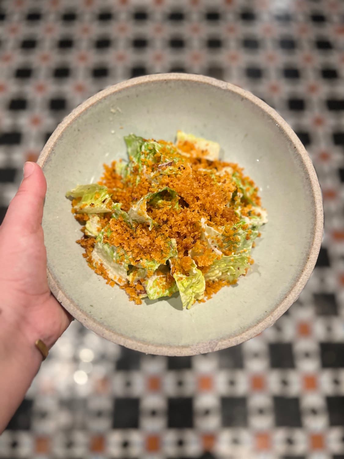 Seasonal salad course held above a patterned kitchen floor